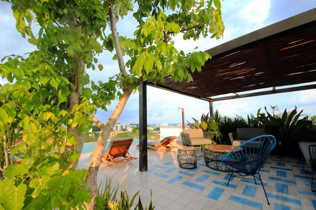 a patio with chairs and a table and trees at Spacious Studio, incredible rooftop with sea view in Playa del Carmen