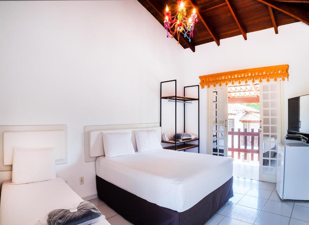 um quarto com 2 camas brancas e uma televisão em Villaê Pousada em Pirenópolis