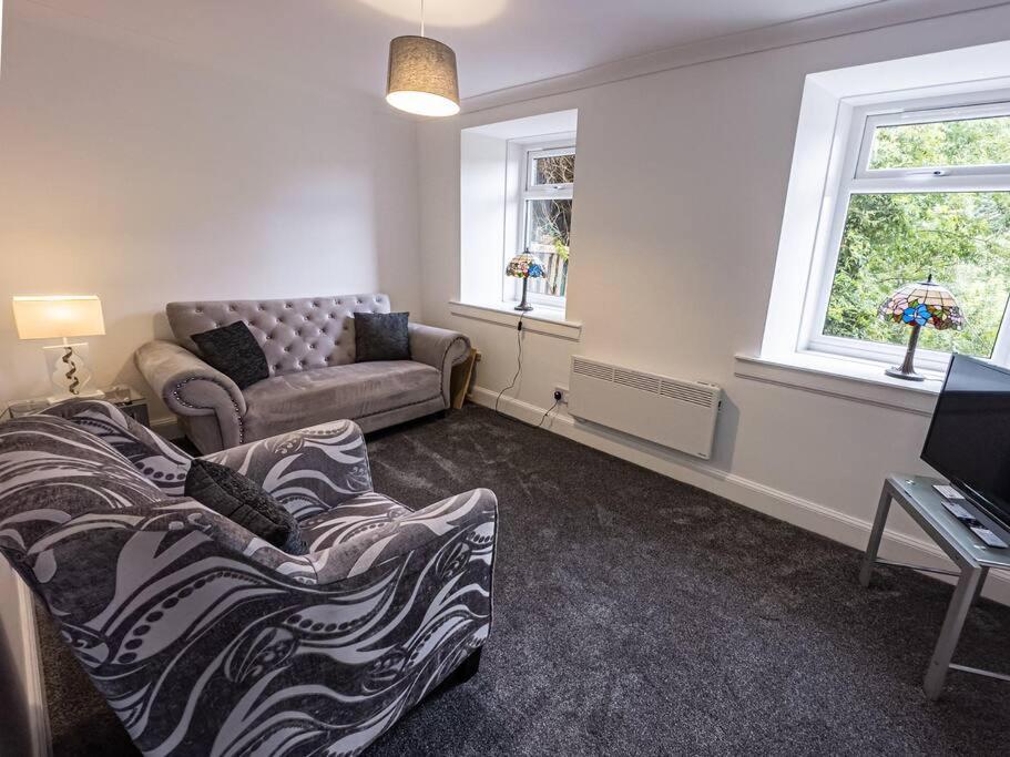 uma sala de estar com um sofá e uma televisão e janela em Riverview Cottage em Lanark