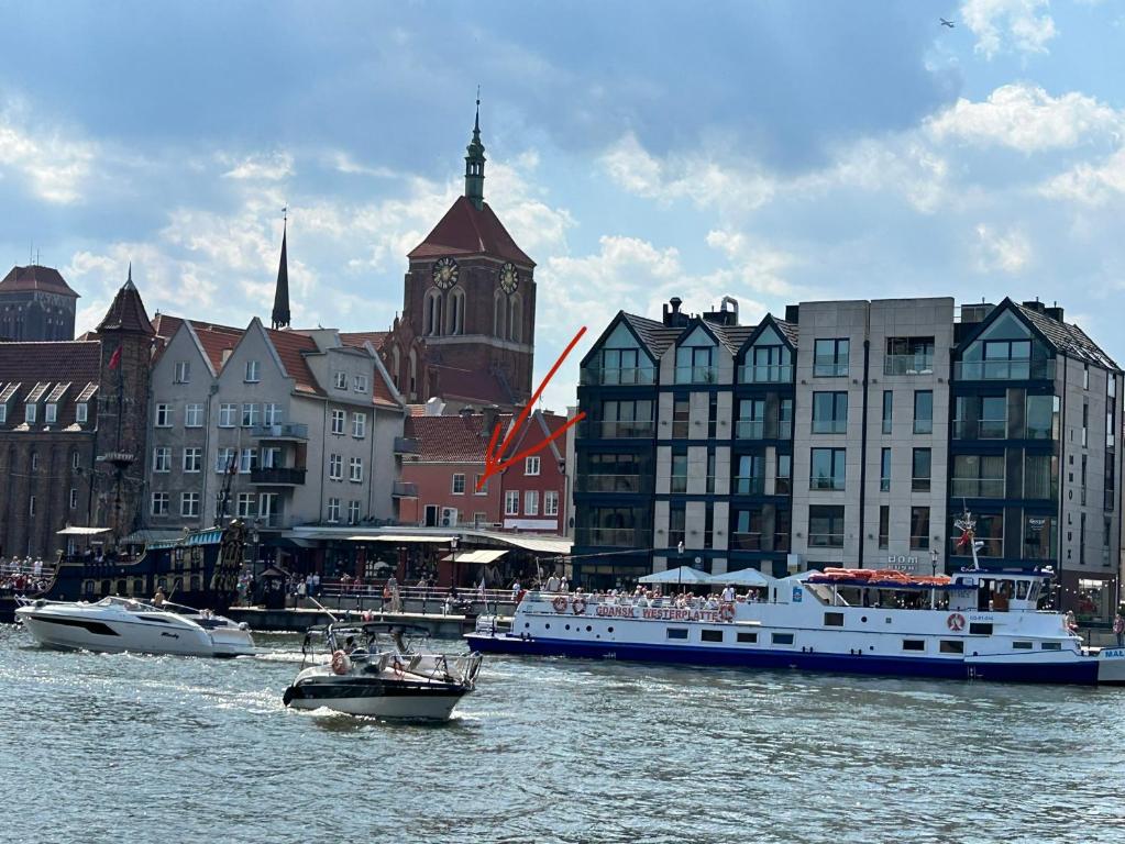 a boat in the water near a city with buildings at Apartament Targ Rybny LUXON Gdansk in Gdańsk