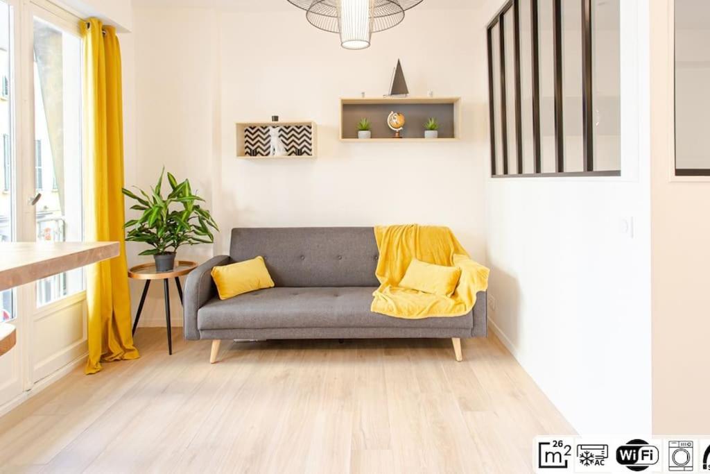 - un salon avec un canapé gris et des oreillers jaunes dans l'établissement #38 Promenade Studio : AC 2 mins de la Plage, à Nice