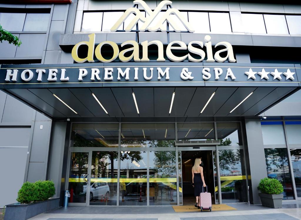 eine Frau geht vor einem Hotel und Spa in der Unterkunft Doanesia Premium Hotel & Spa in Tirana