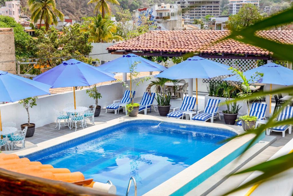 una piscina con sillas y sombrillas azules en Hotel Pueblito Vallarta, en Puerto Vallarta