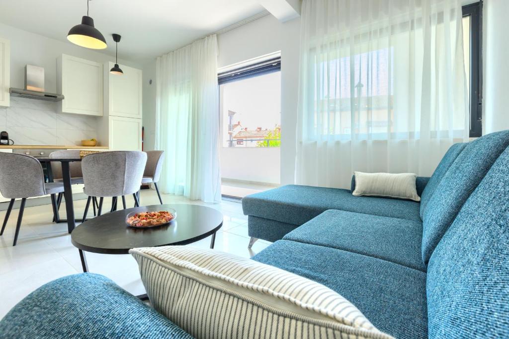 un soggiorno con divano blu e tavolo di Apartments La Scogliera Rovinj a Rovigno (Rovinj)