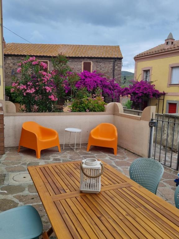 um pátio com uma mesa de madeira, cadeiras e flores em Le petit refuge em Capraia