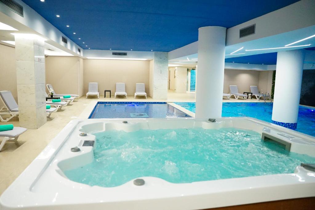 a large bath tub in a room with a pool at Doanesia Premium Hotel & Spa in Tirana