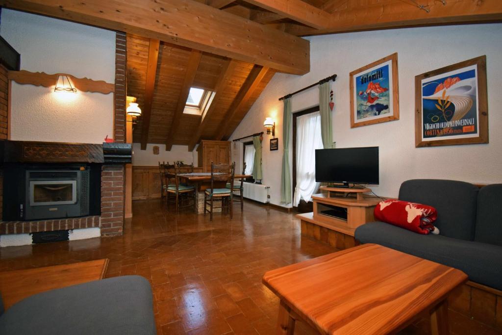 a living room with a couch and a television and a table at La Mansarda in the Dolomites Jacuzzi in Santo Stefano di Cadore