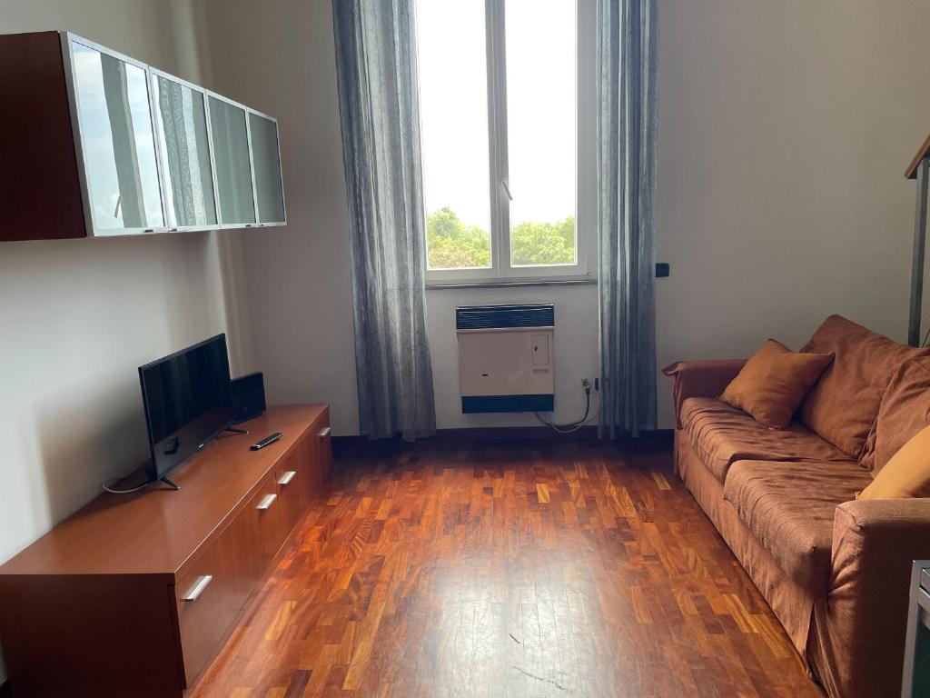 ein Wohnzimmer mit einem Sofa, einem Tisch und einem TV in der Unterkunft Scoglio della Regina, NUOVO, fronte mare, vicino al porto in Livorno