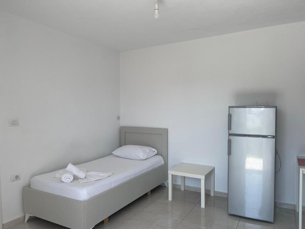 a white bedroom with a bed and a refrigerator at Villa Angelina Ksamil in Ksamil