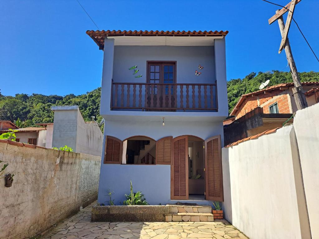 a white house with a balcony on a street at Casa Aconchegante in Paraty