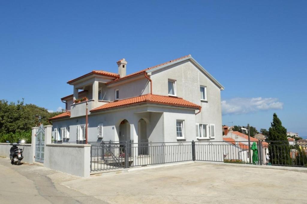 a white house with a fence in front of it at Apartments Marlen in Mali Lošinj