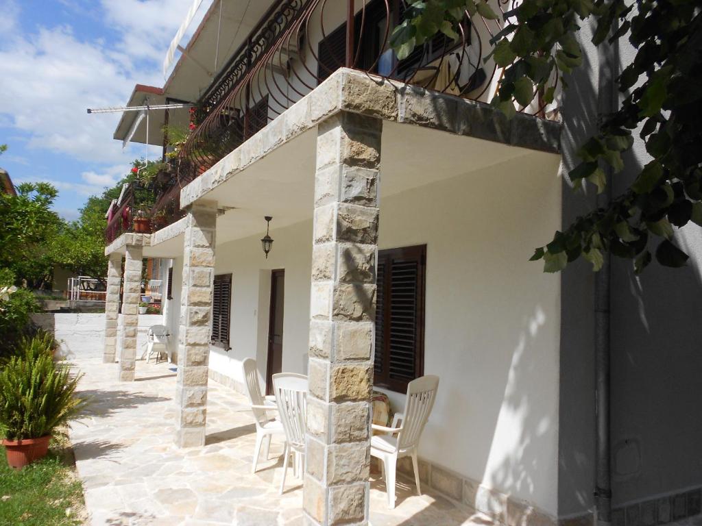 a patio outside of a house with white chairs at Apartments Samardzic in Kotor