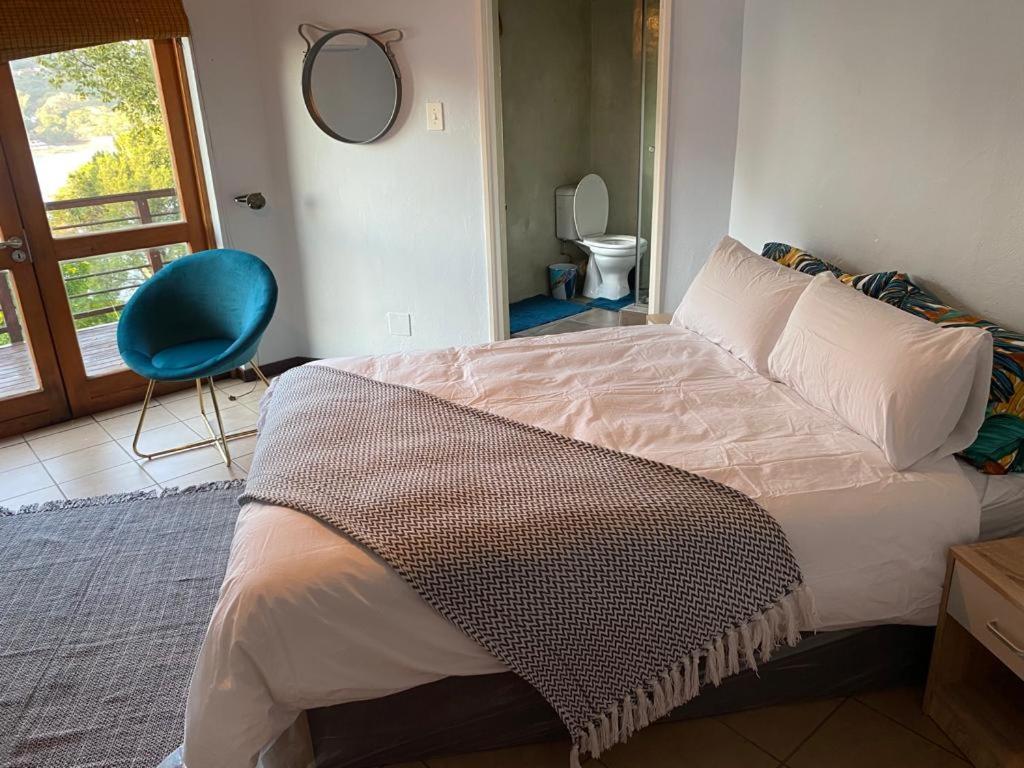 a bedroom with a bed and a blue chair at Manzi Villa in Hartbeespoort