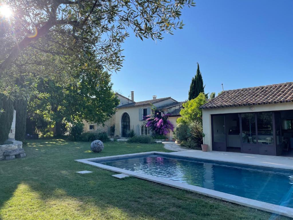 a backyard with a swimming pool and a house at MAS MILLÉSIME - Chambre double - petit déjeuner - piscine - Mas du XVIIIème siècle proche Saint-Rémy-de-Provence in Mas blanc des Alpilles