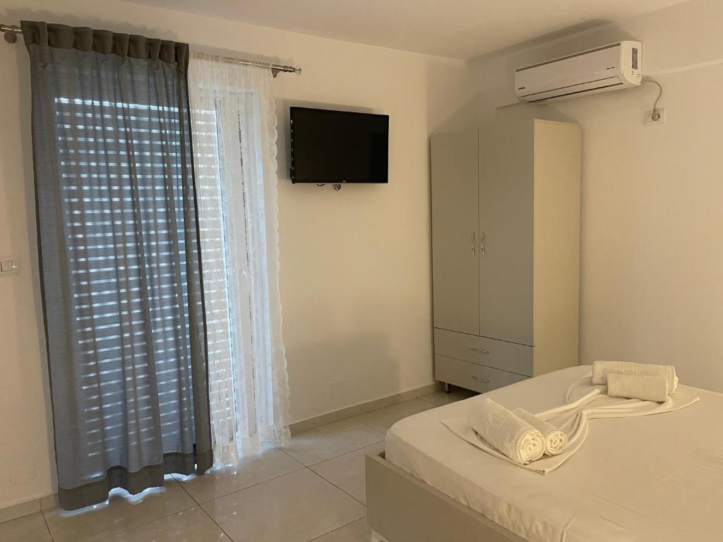 a bedroom with a bed and a television and a window at Villa Angelina Ksamil in Ksamil