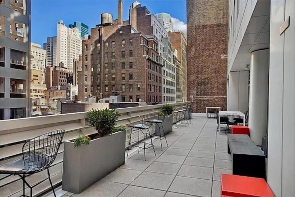 a balcony with chairs and tables on a building at Stylish 2BD with Washer and Dryer near Times Square in New York