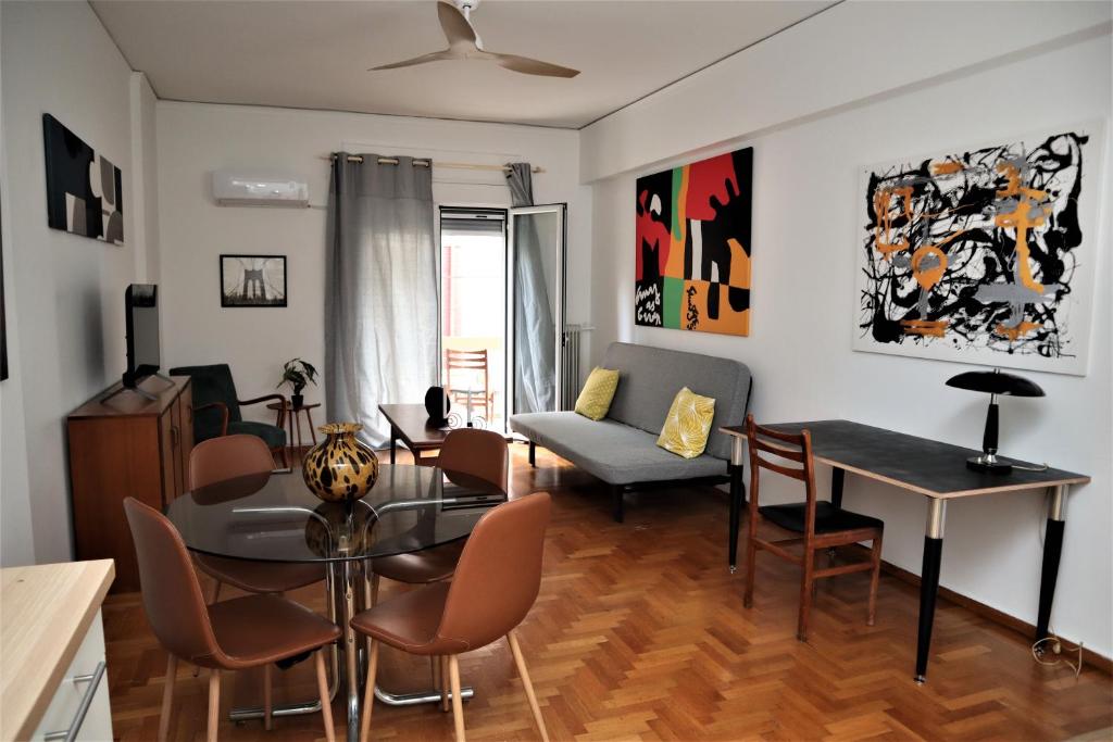 ein Wohnzimmer mit einem Tisch, Stühlen und einem Sofa in der Unterkunft Cozy 2 Bedroom apt @Panormou Metro/Erytros Stavros in Athen