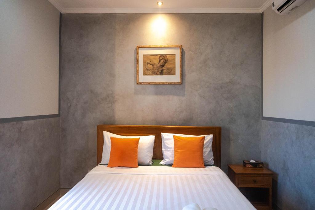 um quarto com uma cama com almofadas laranja e branca em Kubu Indah Homestay Sanur em Sanur