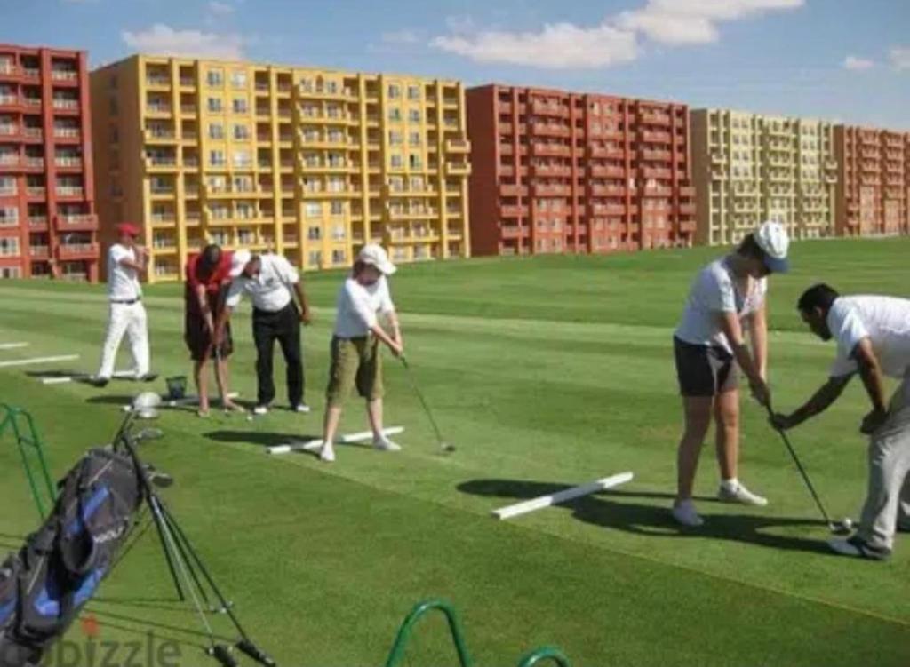 a group of people playing golf on a golf course at استديو راقي ارضي بجنينة للعائلات فقط in El Alamein