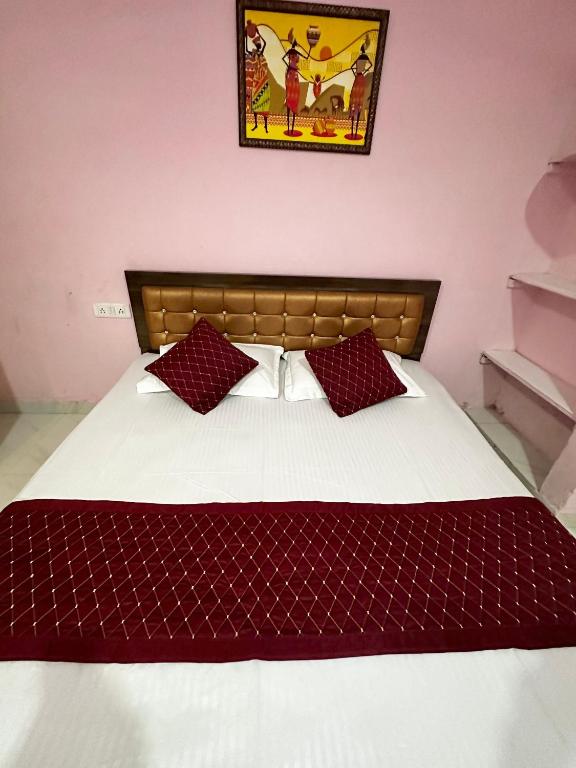 a bedroom with a bed with a red and white comforter at Hotel Tathastu in Rāmtek