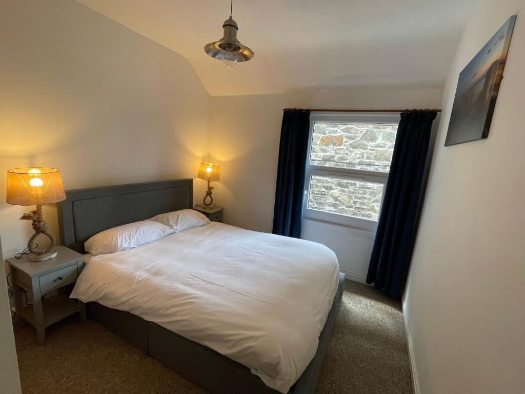 a small bedroom with a bed and a window at Glanywerydd Cottage in Barmouth