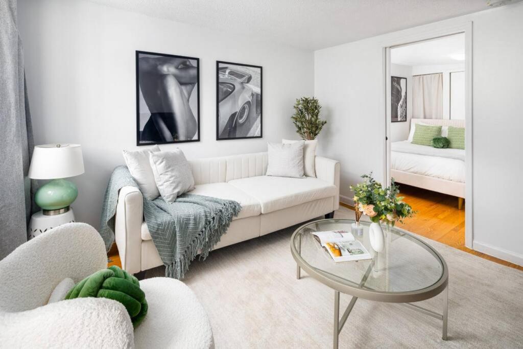 uma sala de estar com um sofá branco e uma mesa de vidro em Stylish One-Bedroom with In-unit Laundry in East Village em Nova York