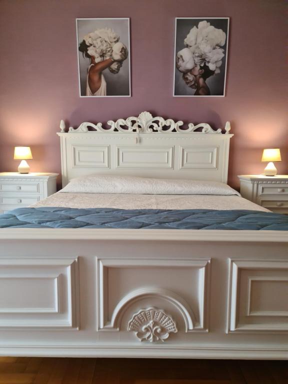 a white bed in a bedroom with two pictures on the wall at V.home in Abano Terme