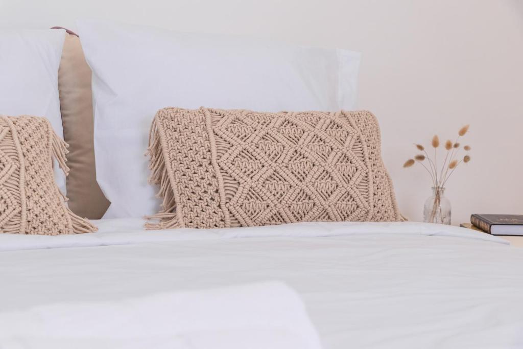 Una cama con sábanas blancas y almohadas. en Casa Quintal da Aldeia, en Alcobaça