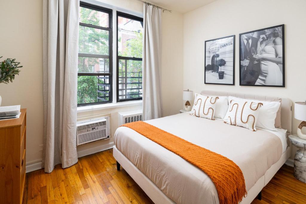 a bedroom with a large bed and two windows at Cozy and Modern One-Bedroom Apartment in New York