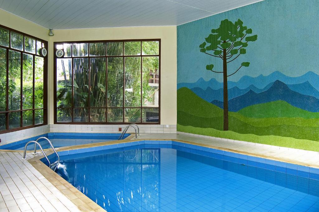 a large swimming pool with a tree mural on the wall at Hotel Bühler in Visconde De Maua