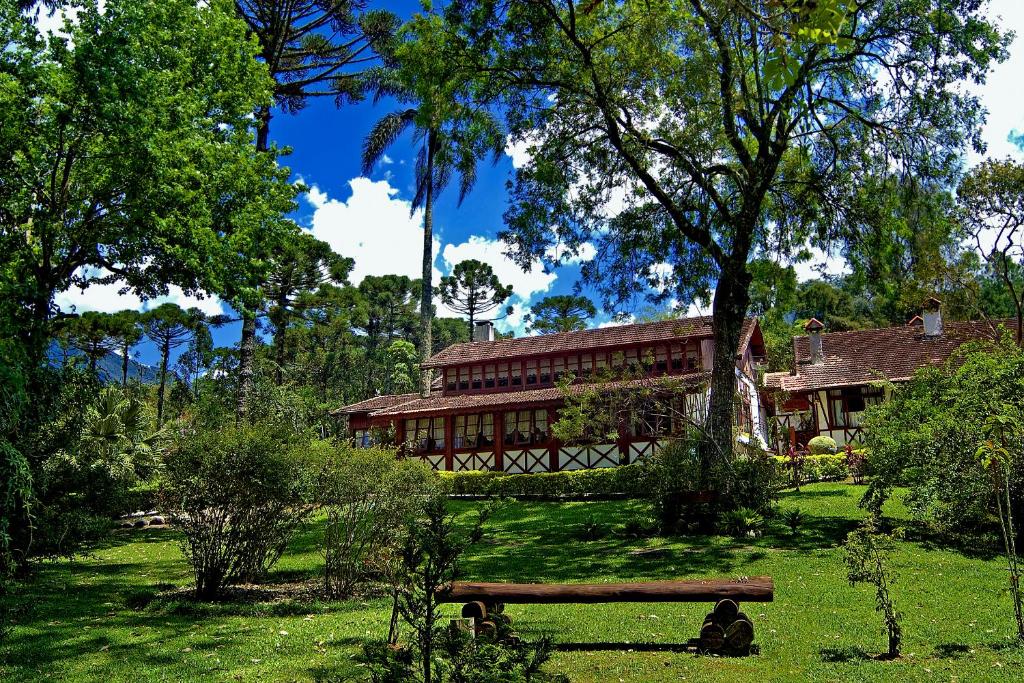 ein Haus inmitten eines Gartens mit einer Bank in der Unterkunft Hotel Bühler in Visconde De Maua