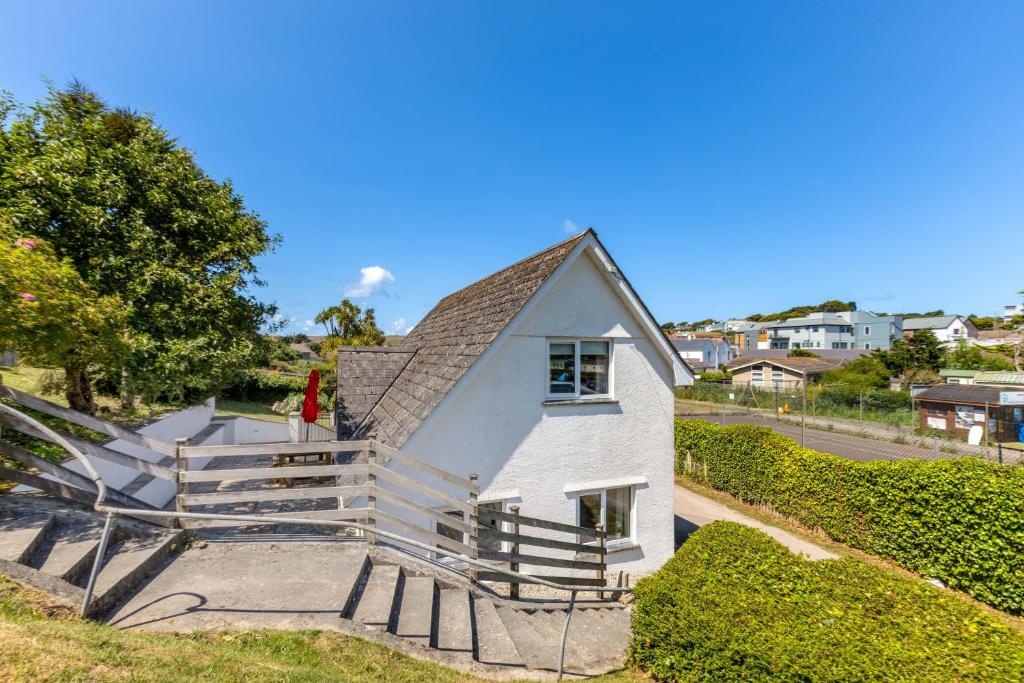a white house with a staircase in a yard at Baywatch Sands in Wadebridge