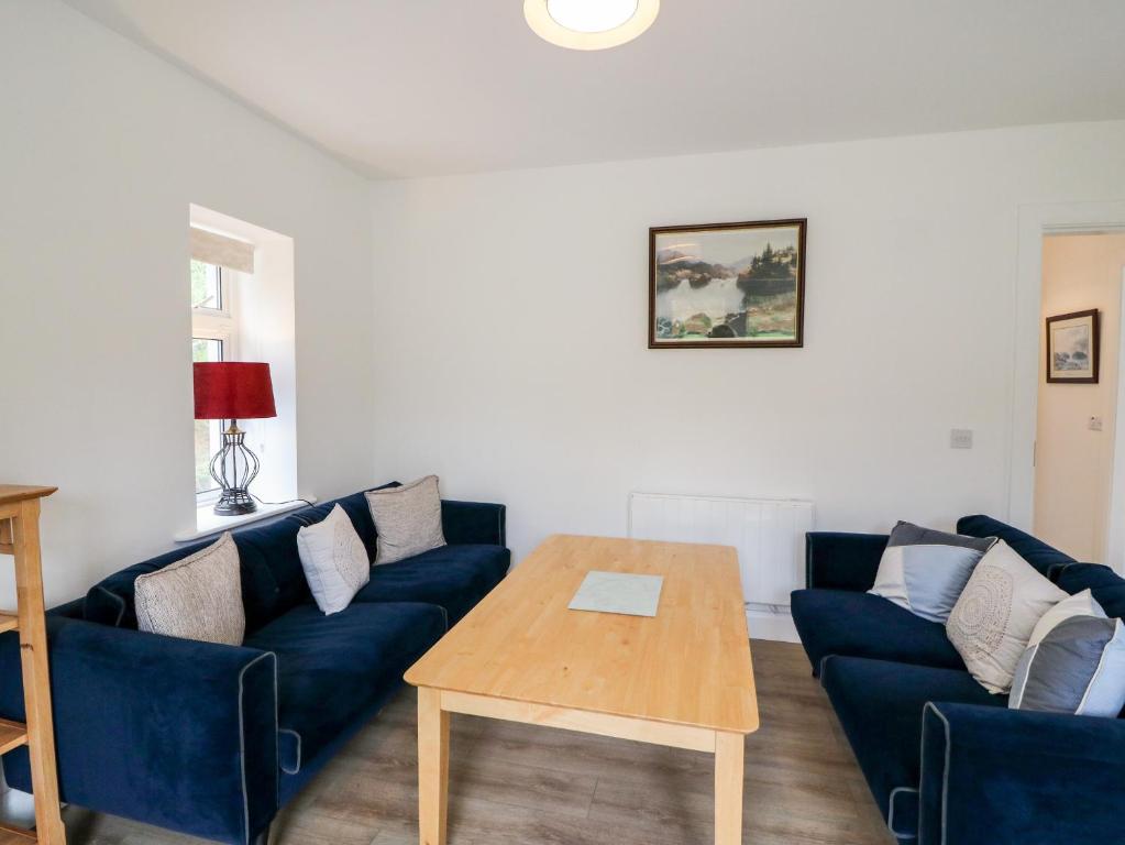 ein Wohnzimmer mit blauen Sofas und einem Holztisch in der Unterkunft Ahiohill Meadows 