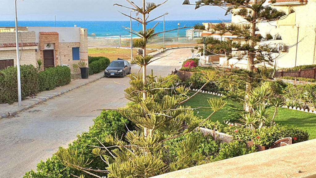 une voiture garée dans une rue à côté de l'océan dans l'établissement Stunning 5-Bedroom Villa with Breathtaking Sea Views & Roof Penthouse at Badr resort North Coast El Alamein !! الساحل الشمالي, à El Alamein