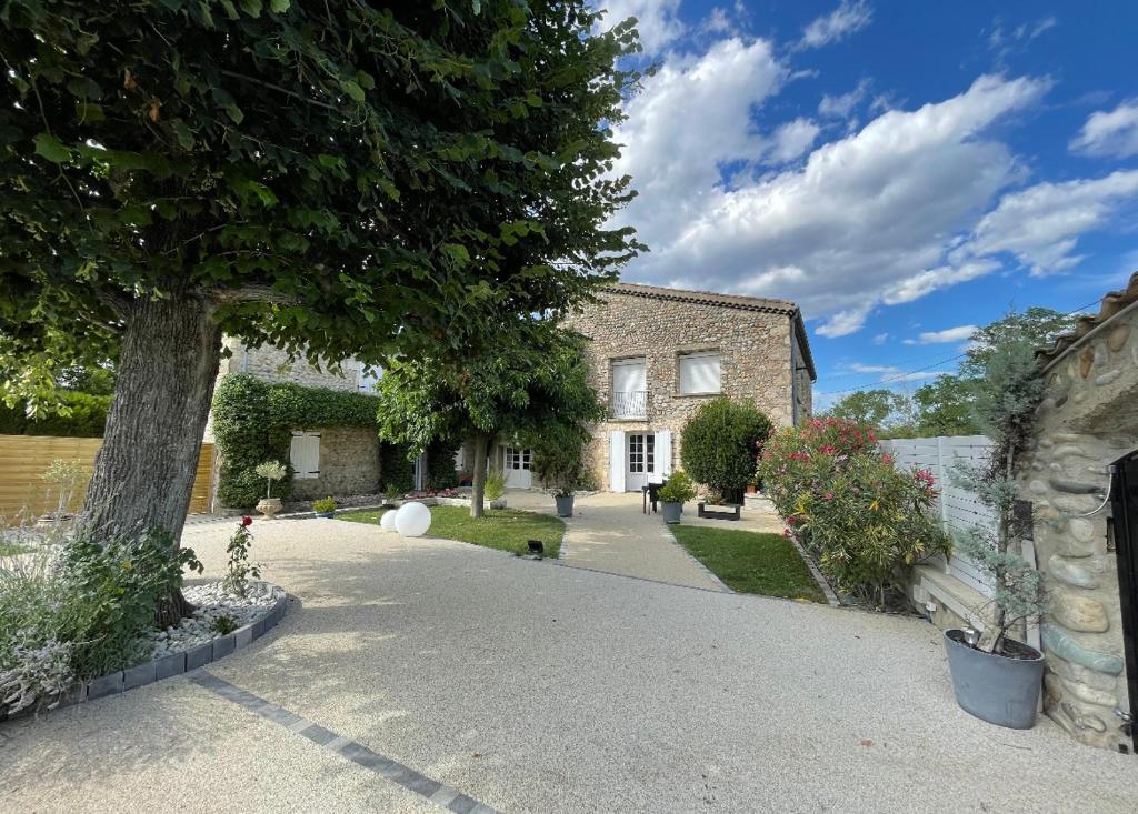 a brick house with a tree and a driveway at Petite'Escale in Charmes-sur-Rhône