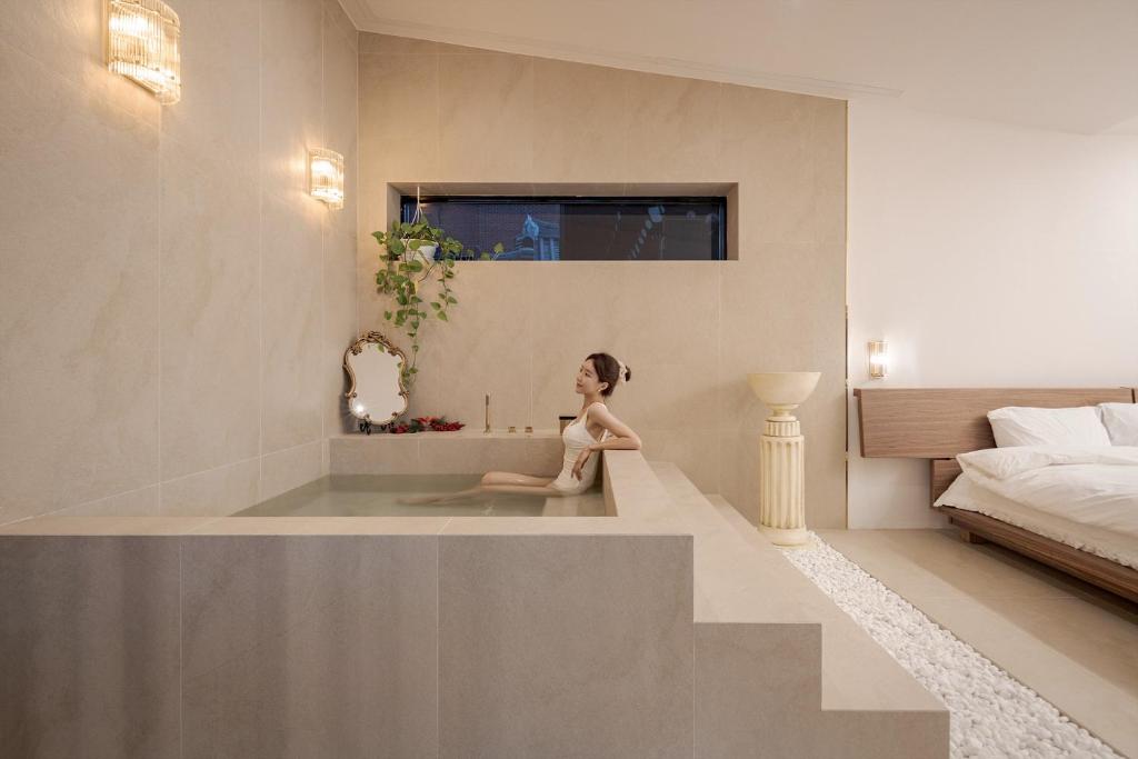 Ein kleines Mädchen, das in einer Badewanne im Schlafzimmer sitzt. in der Unterkunft Jeonju Hanok Village, Maison14 in Jeonju