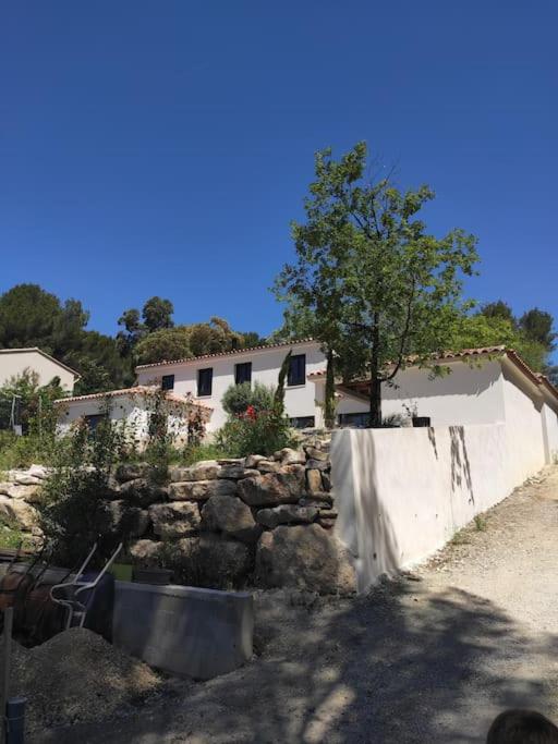 un mur en pierre avec un arbre à côté d'un bâtiment dans l'établissement Villa spacieuse avec piscine en Provence, à Ventabren