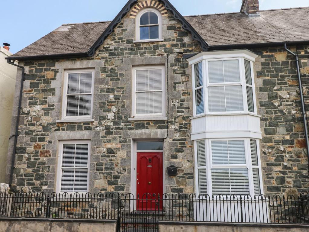a brick house with a red door and white windows at 2 Ashgrove in Dinas