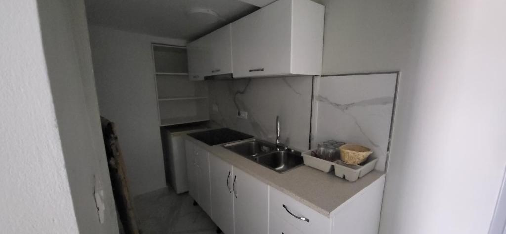 a white kitchen with a sink and a counter at Jon rooms in Himare