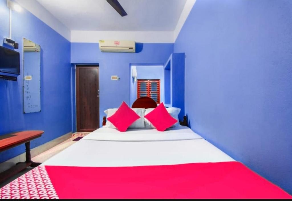 Cette chambre bleue comprend un grand lit avec une couverture rouge. dans l'établissement Labanya Lodge, à Konârak