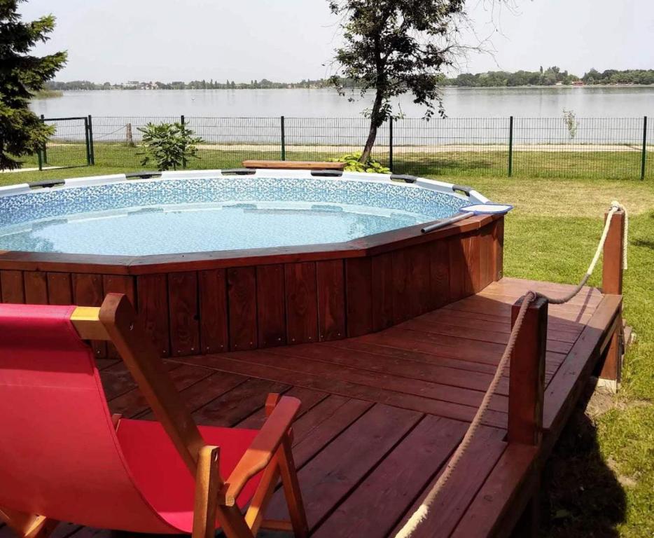 a hot tub on a wooden deck with a chair at OBALA apartman in Subotica