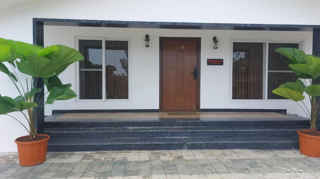 a front door of a house with two potted plants at HillTop in green meadows yercaud in Yercaud