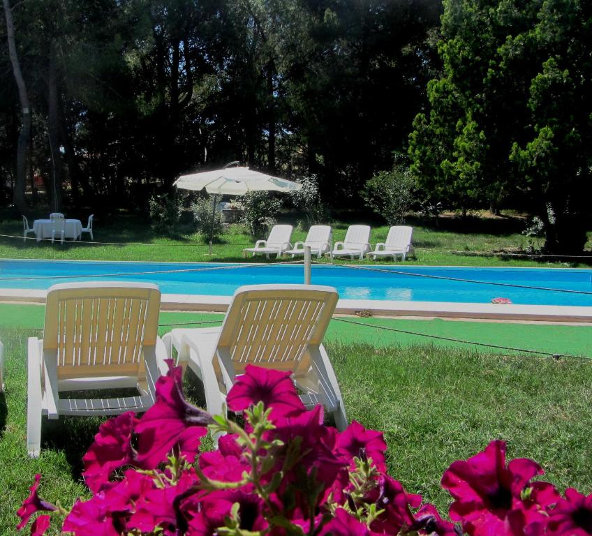 two chairs and an umbrella next to a swimming pool at Feudo Tudia in Landro