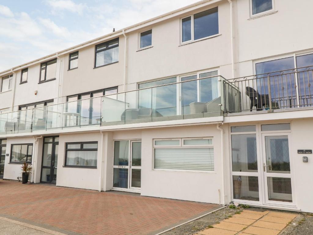 an exterior view of a white building with a balcony at 11 Min Y Mor in Pwllheli