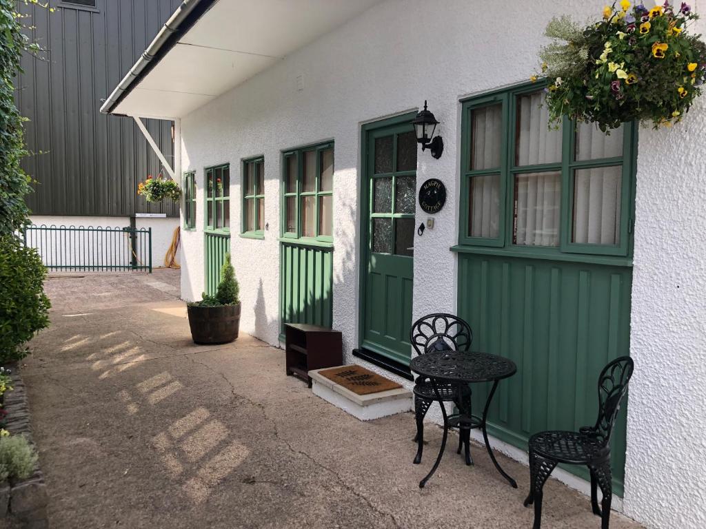 dom z zielonymi drzwiami oraz stołem i krzesłami w obiekcie Deanwood Holiday Cottages w mieście Yorkley