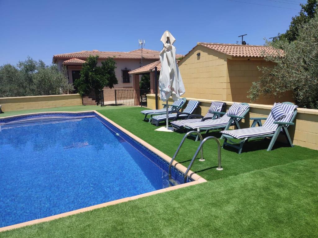塞特尼的住宿－LOS ABUELOS，一个带草坪椅和遮阳伞的游泳池