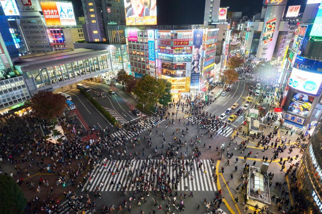 uma grande multidão de pessoas atravessando uma rua em uma cidade em Hotel Indigo Tokyo Shibuya em Tóquio