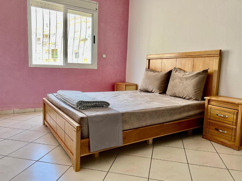 1 dormitorio con cama con marco de madera y ventana en Cozy Apartment in Salam center, en Agadir