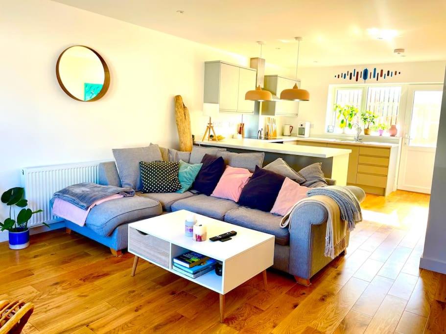 a living room with a blue couch and a white table at Modern chic summer holiday retreat. in Newquay