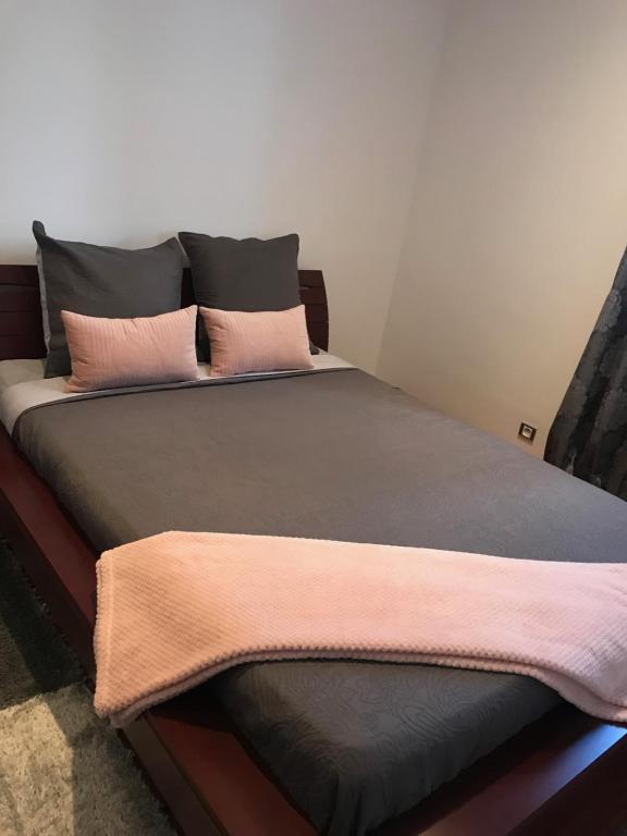 a bed with pink and grey pillows on it at Nice Stay - La Noue in Villeneuve-la-Garenne